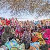 تتلقى مجموعة من النساء والأطفال السودانيات اللاجئات المساعدة الغذائية في مخيم كولبوس للاجئين في تشاد، بدعم من برنامج الأغذية العالمي (WFP). يجلسون تحت الأشجار، يحملون أكياسًا من المواد الغذائية بما في ذلك الخضروات والأطعمة المغذية المتخصصة للأمهات والأطفال.