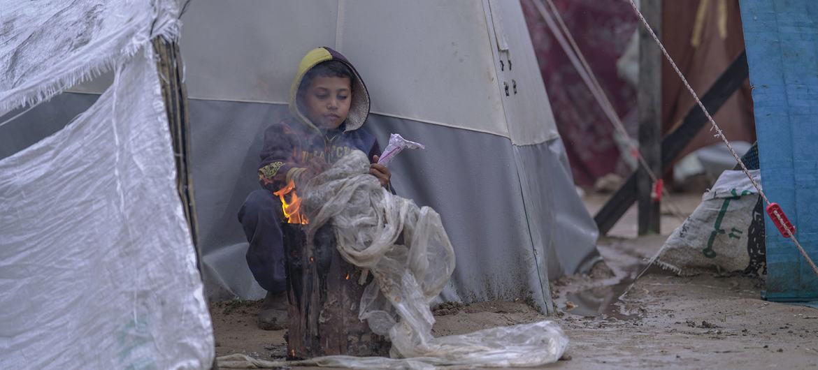 طفل يحتمي من البرد في مخيم  مؤقت للنازحين في غزة.
