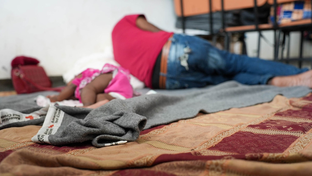 Una niña y un adulto duermen en un centro para personas desplazadas en Haití.
