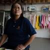 Mariyam Tadein sits in her clothing shop, looking up with a worried expression.