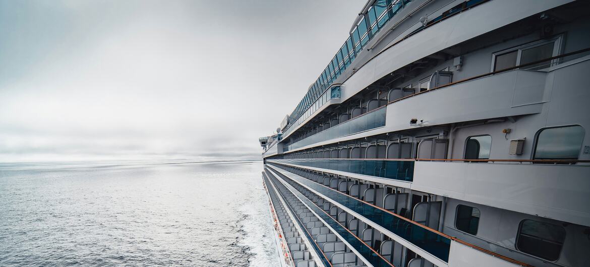 Un gran crucero blanco navega por el océano en un día nublado.