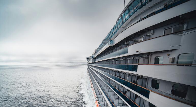 Un gran crucero blanco navega por el océano en un día nublado.