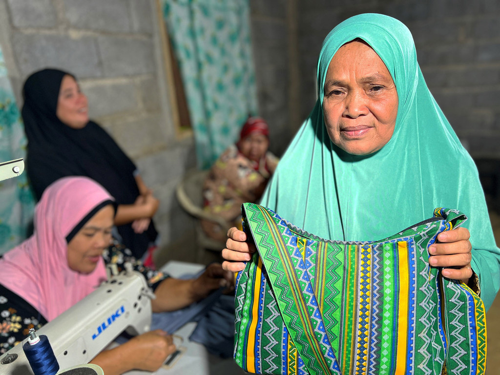 Asnia Dalan holds a bag she sewed following the training she received.