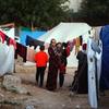 Une femme tient un enfant dans ses bras dans un camp de tentes à Gaza.