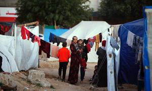 Una mujer sostiene a un niño en brazos en un campamento de tiendas de campaña en Gaza.