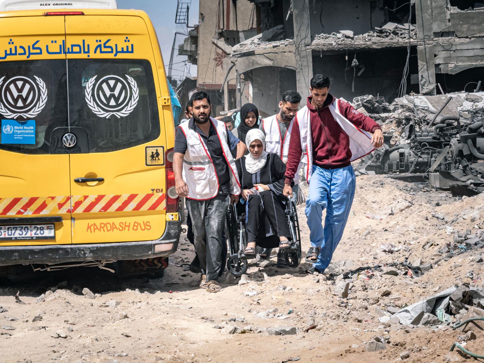 Une femme en fauteuil roulant est transportée à travers les décombres à Gaza.
