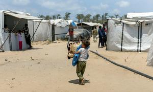Un niño lleva sus pertenencias en el campo de desplazados de Al Mawasi, en Gaza.