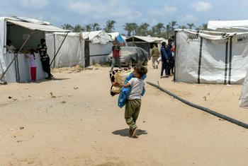 Un niño lleva sus pertenencias en el campo de desplazados de Al Mawasi, en Gaza.