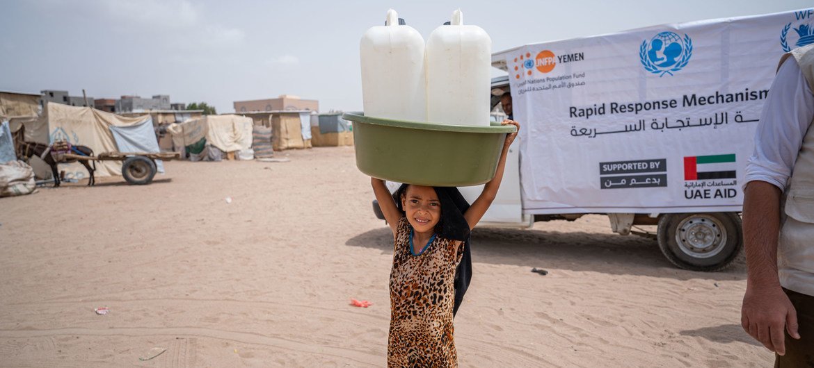 طفلة في الثامنة من العمر تحمل مستلزمات الإغاثة في مخيم الشعب للنازحين داخليا في اليمن.