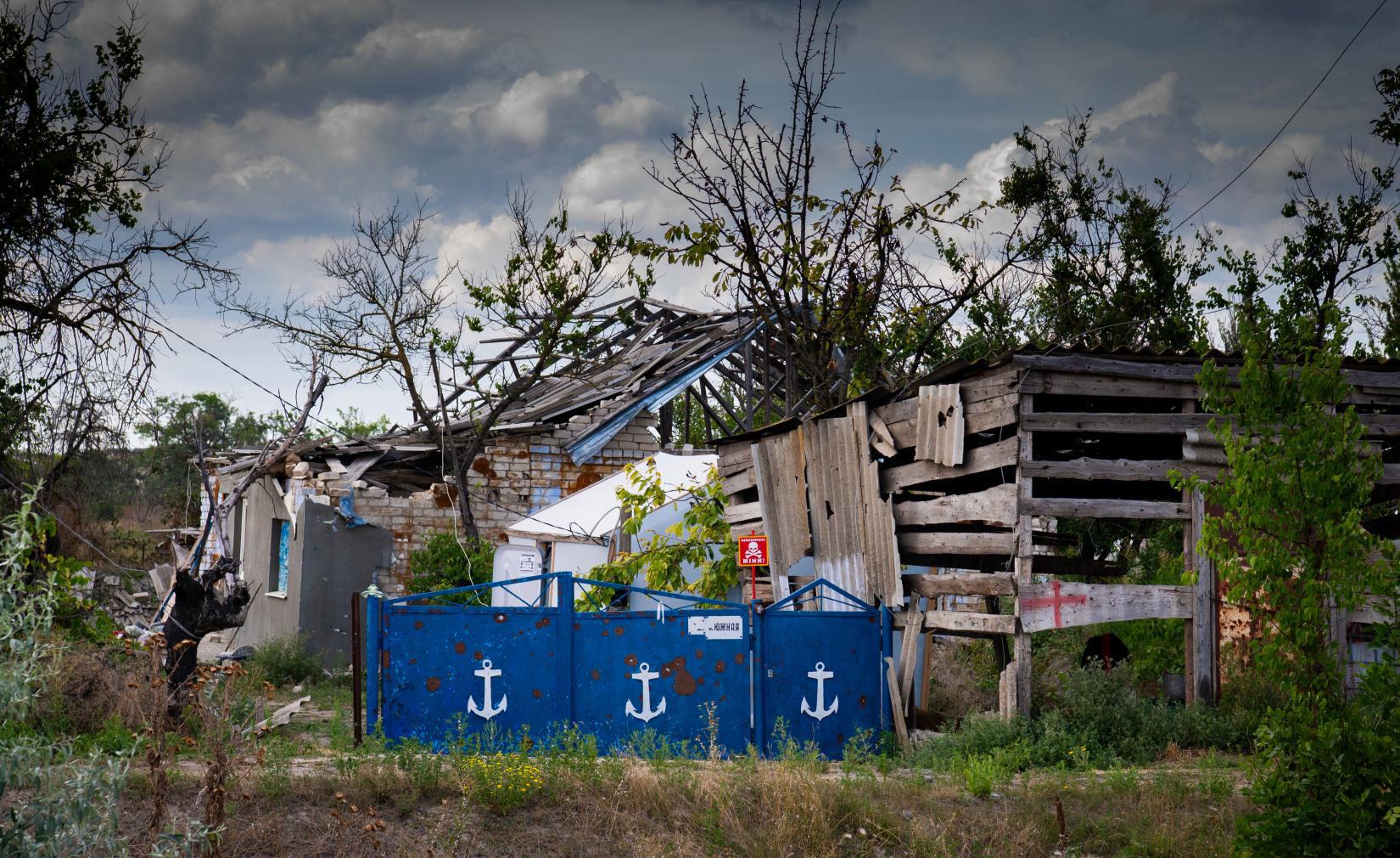 A landmine warning sign behind a fence of a destroyed house in Posad-Pokrovske in the Kherson region of Ukraine.