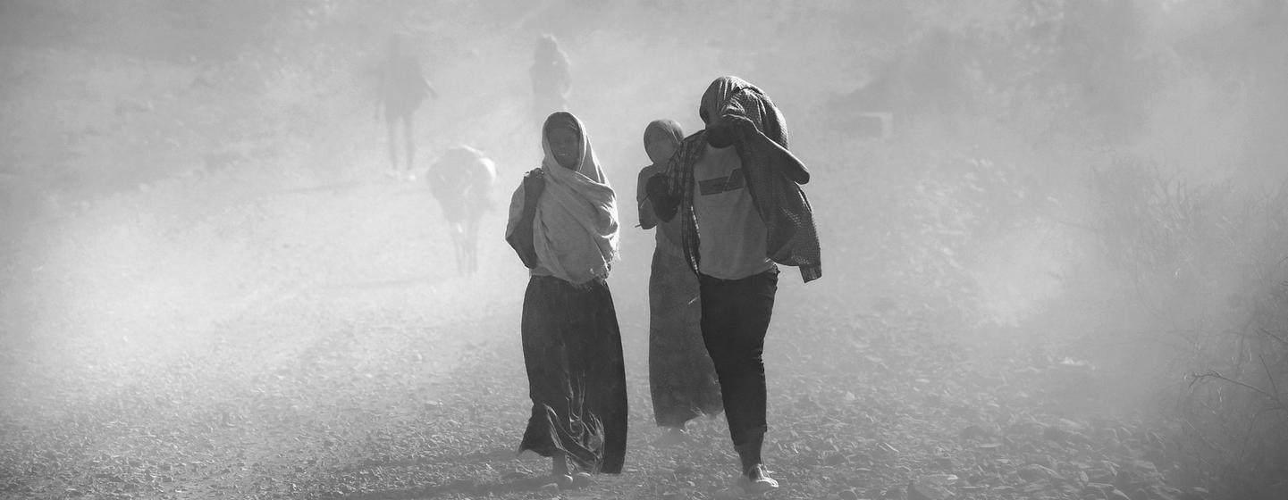 Des personnes marchent sur une route poussiéreuse à Gondar Ouest, en Éthiopie, sur une photographie en noir et blanc réalisée pour le concours du calendrier WMO 2024.