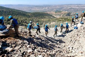 جنود حفظ السلام الأمم المتحدة ، يرتدون خوذات وسترات زرقاء، ينقلون الإمدادات عبر الأنقاض على طريق متضرر في جنوب لبنان.