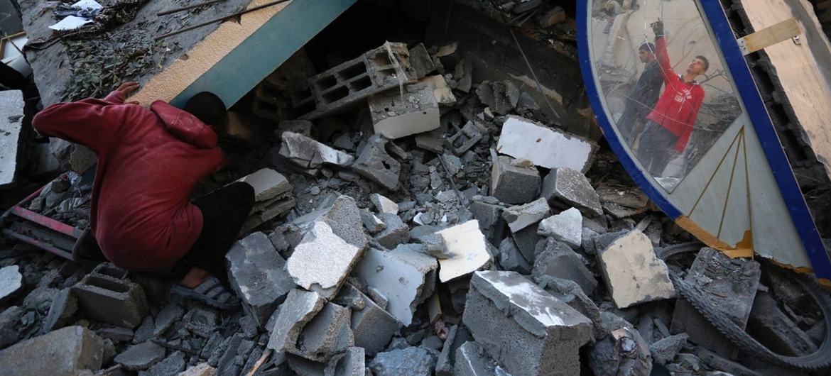 Varias personas buscan sus pertenencias entre los escombros del campo de refugiados de Nuseirat, en Gaza.