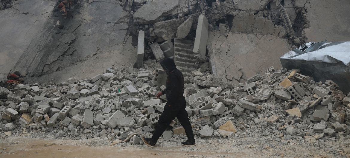 رجل يسير أمام مبنى تضرر من الزلزال في إدلب بسوريا.