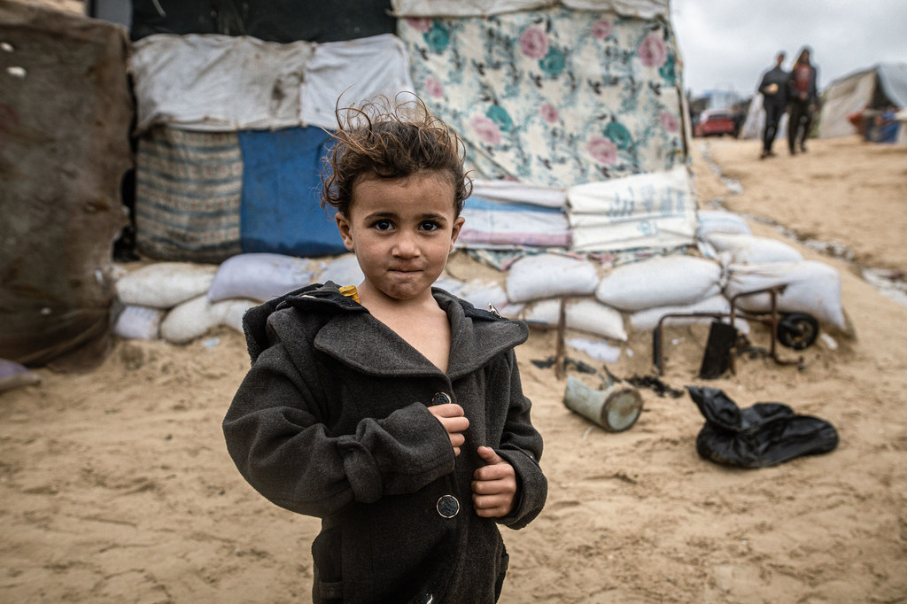 Un enfant à côté d'abris érigés sur une plage de Gaza.