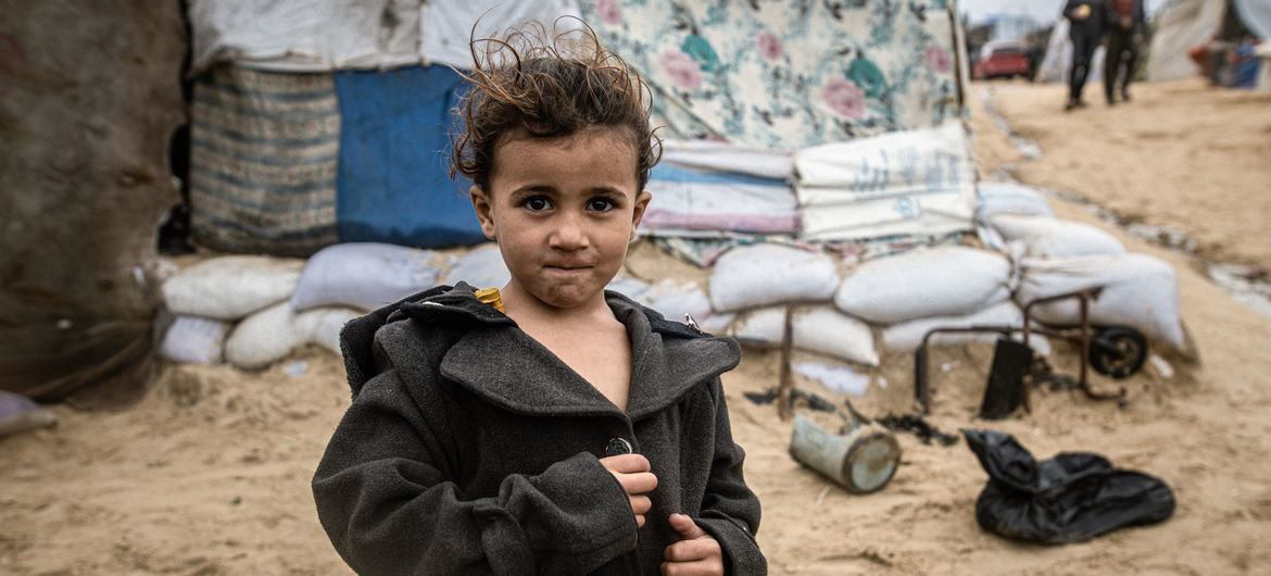Un enfant à côté d'abris érigés sur une plage de Gaza.