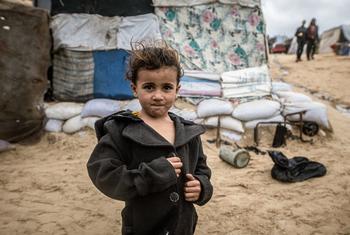 Un enfant à côté d'abris érigés sur une plage de Gaza.