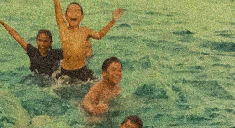 A group of joyful children swimming and playing in the clear blue waters of Palau, highlighting the island's natural beauty and the importance of disaster resilience.