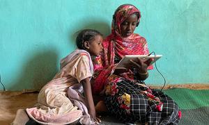 Girls use a solar-powered tablet at an e-learning centre in Jabalain, Sudan.