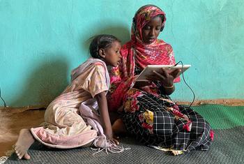 Niñas usando una tableta que funciona con energía solar en un centro de aprendizaje electrónico de Jabalain, en Sudán.