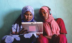 Two young women in Sudan play educational games on a solar-powered tablet. 