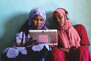 Two young women in Sudan play educational games on a solar-powered tablet. 