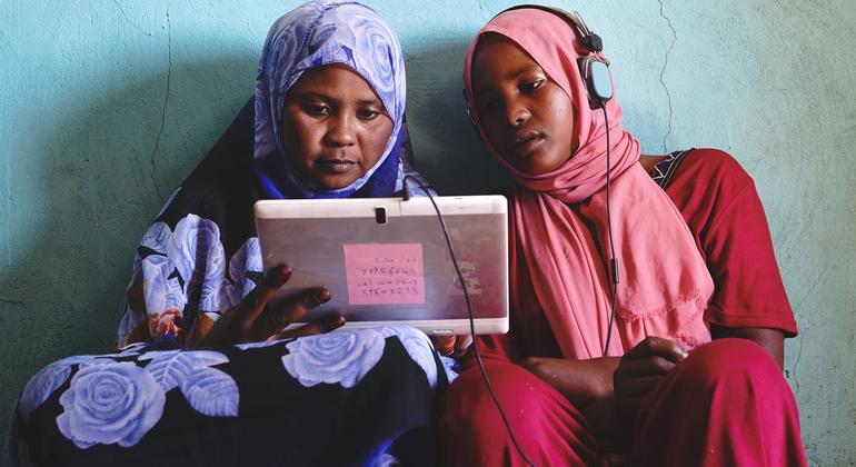 Dos jóvenes sudanesas disfrutan de juegos educativos en una tableta que funciona con energía solar. 