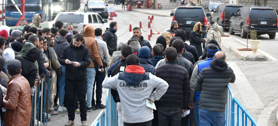 لبنان اور شام کے مابین مسناہ بارڈر کراسنگ پر بے گھر مردوں ، خواتین اور بچوں کا ایک بڑا گروہ لبنان اور شام کے مابین مسناہ بارڈر کراسنگ پر قطار میں انتظار کر رہا ہے۔ وہ موسم سرما کے کوٹ میں بندھے ہوئے ہیں ، کچھ دستاویزات رکھتے ہیں ، جب وہ اسرائیلی بمباری سے بچنے کے لئے شام کے پار ہونے کا انتظار کر رہے ہیں۔ چیک پوائنٹ پر پس منظر میں ایک نیلی بس اور کئی کاریں نظر آرہی ہیں۔