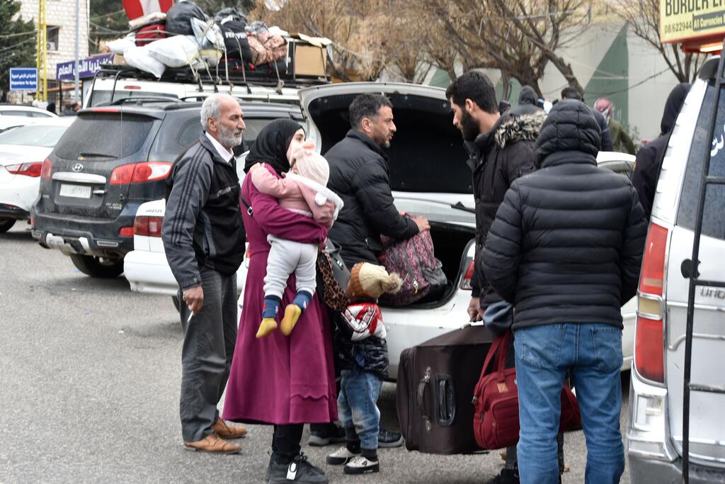 Une famille de réfugiés avec des bagages attend au poste frontalier de Masnaa au Liban pour entrer en Syrie, fuyant les bombardements israéliens.