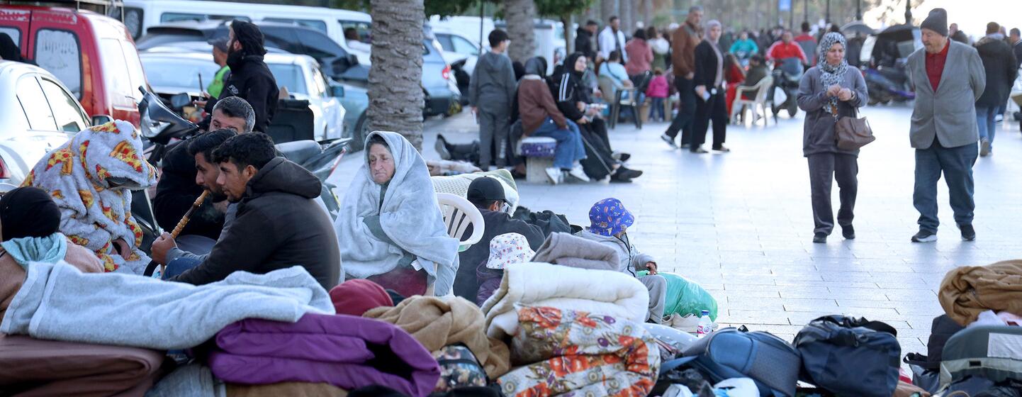 Des familles déplacées, y compris des enfants et des adultes, sont assises dans une rue de Beyrouth, au Liban, entourées de leurs affaires et de leurs couvertures à la suite des avertissements d'évacuation.