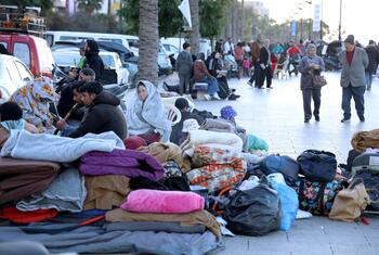 Des familles déplacées, y compris des enfants et des adultes, sont assises dans une rue de Beyrouth, au Liban, entourées de leurs affaires et de leurs couvertures à la suite des avertissements d'évacuation.