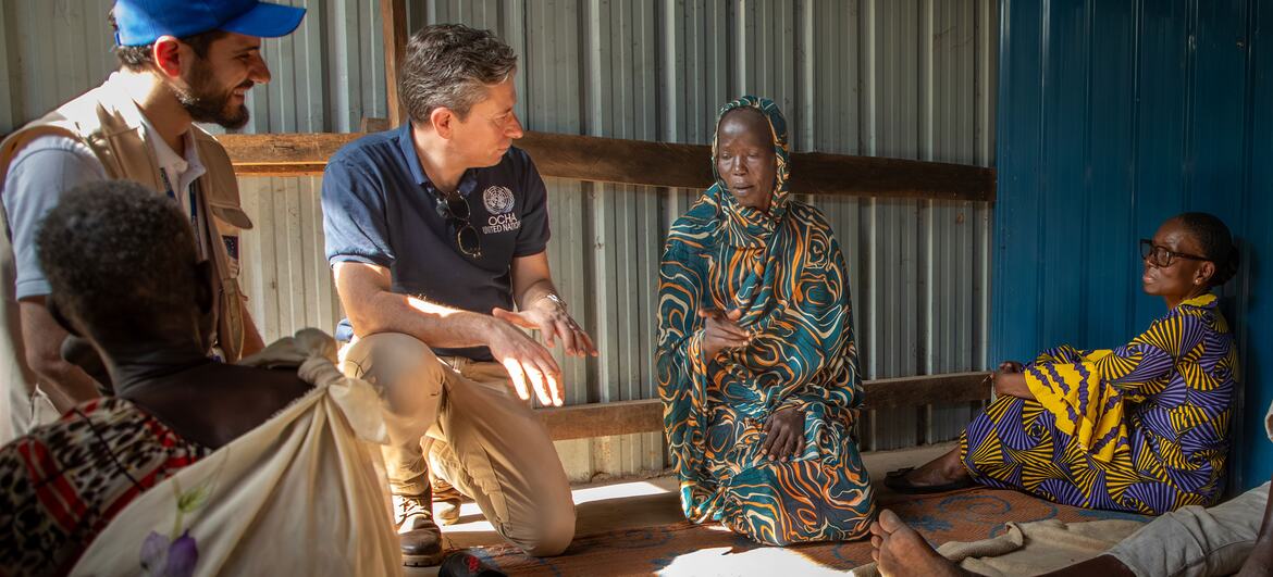 USG Tom Fletcher crouching to talk with Naketta Josphine, a displaced woman from Sudan, inside her temporary shelter at the Bulukat Transit Centre in Malakal, South Sudan.
