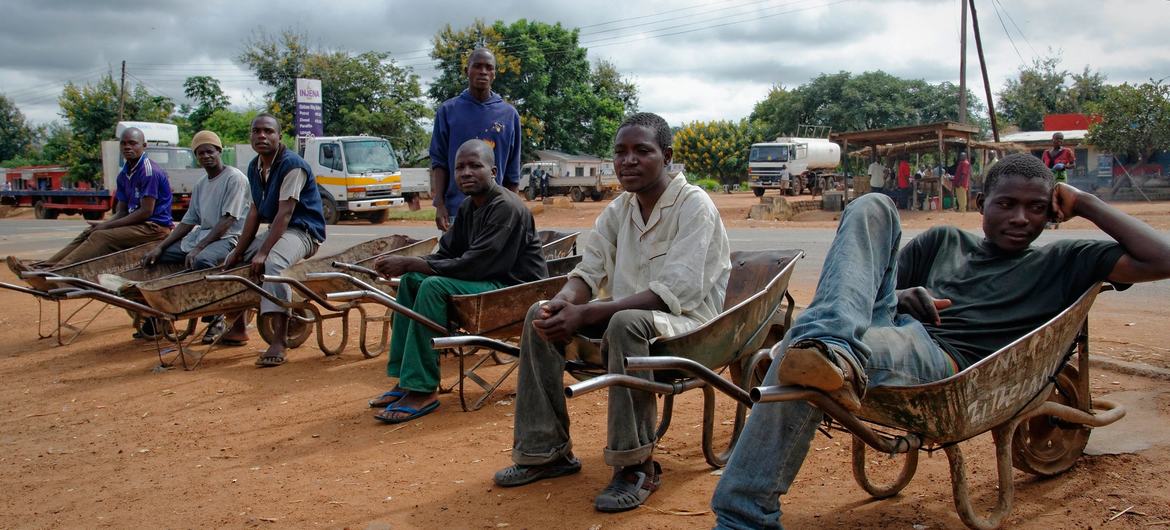 Des hommes assis dans leurs brouettes attendent de travailler sur le bord de la route dans la région de Kasungu, au Malawi.
