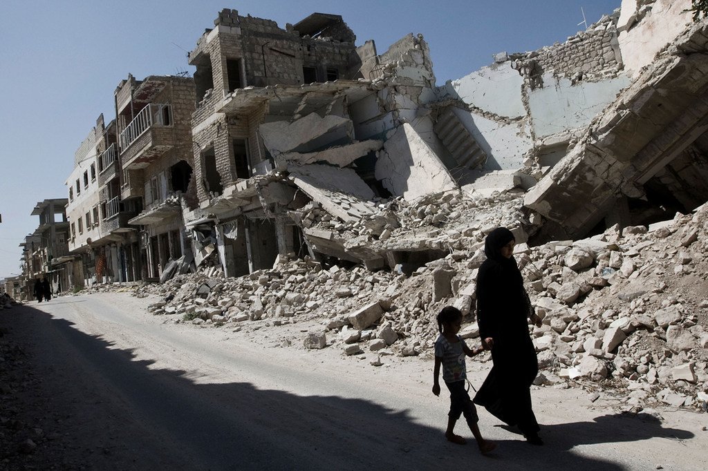 فتاة وامرأة يمشيان بالقرب من بنايات مدمرة في مدينة معرة النعمان بريف إدلب، سوريا.