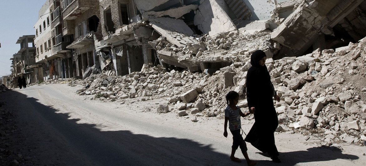 A young girl and a woman walk past destroyed buildings in Idlib Governerate in northwest Syria.