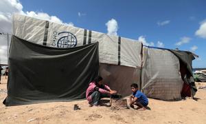 Deux enfants jouent devant un abri à Gaza fabriqué à partir de matériaux provenant notamment de l'ONU.