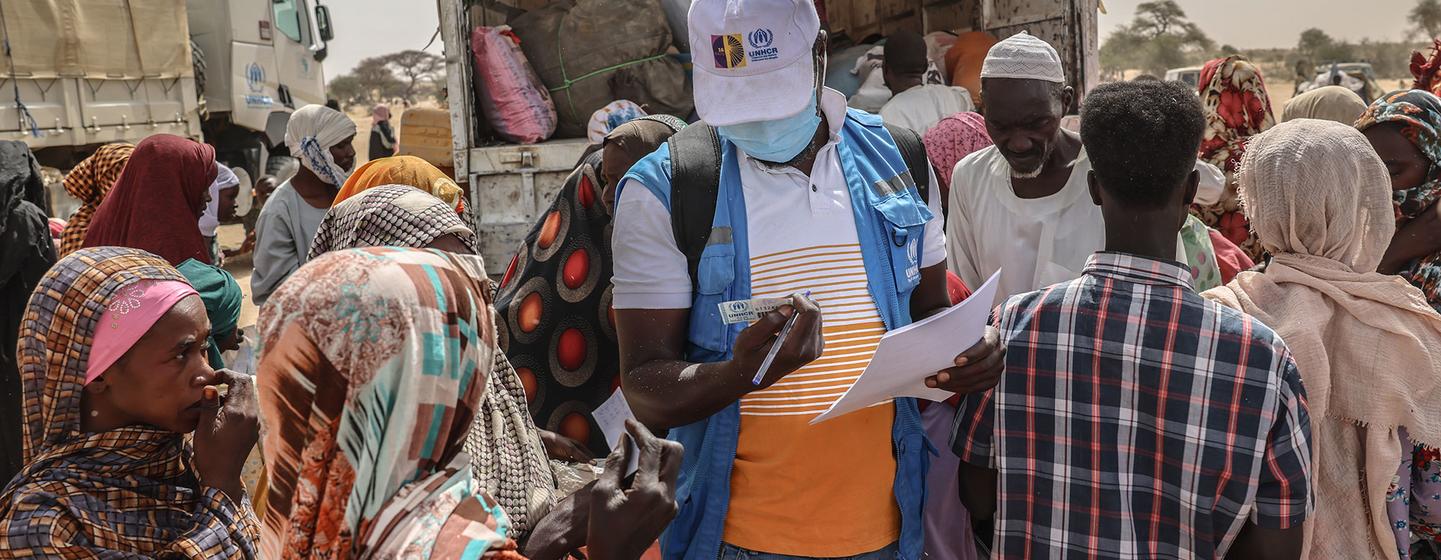 Un membre du personnel du HCR vérifie les documents de réfugiés soudanais nouvellement arrivés sur un site de transit près du poste frontière de Tine, au Tchad.