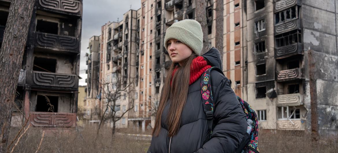 A 13-year-old girl walks past buildings damaged by the shelling in Irpin, Ukraine. 