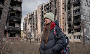 A 13-year-old girl walks past buildings damaged by the shelling in Irpin, Ukraine. 