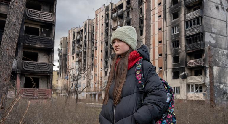 Menina de 13 anos passa por prédios danificados pelo bombardeio em Irpin, na Ucrânia.