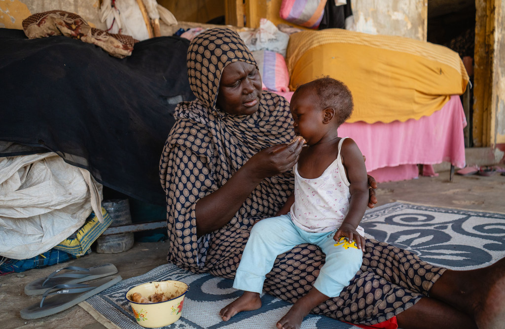 Une femme nourrit un enfant dans une école utilisée comme point de rassemblement pour les personnes déplacées à Port-Soudan.