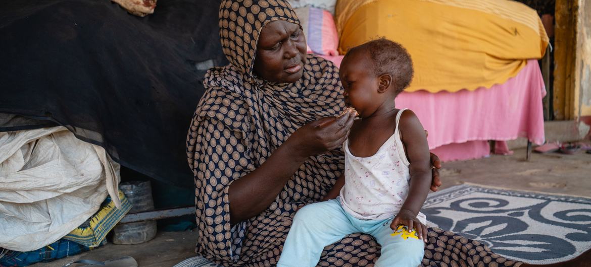 Uma mulher alimenta uma criança em uma escola usada como ponto de encontro para pessoas deslocadas em Port Sudan