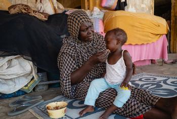 Una mujer da de comer a un niño en una escuela utilizada como punto de encuentro para desplazados en Puerto Sudán.