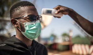 A man's temperature is taken in Mali to check against a possible COVID-19 infection.  
