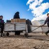 सीरिया के पूर्वोत्तर क्षेत्र में स्थित अल होल शिविर में एक परिवार, यूनीसेफ़ की तरफ़ से मिले सर्दियों के कपड़े ले जाते हुए.