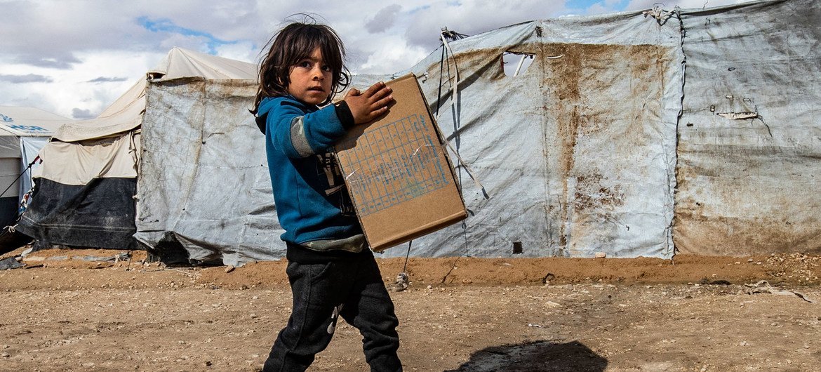 A child carries winter clothing kits, distributed by UNICEF, in Al-Hol camp in northeastern Syria.