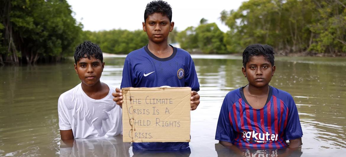 Des adolescents posent avec une pancarte sur laquelle est écrit « La crise climatique est une crise des droits de l'enfant » dans une zone de mangrove aux Maldives.