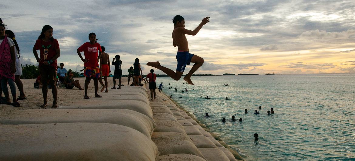 Des enfants de l'île de Tuvalu, dans l'océan Pacifique, jouent dans une zone côtière protégée par des sacs de sable.