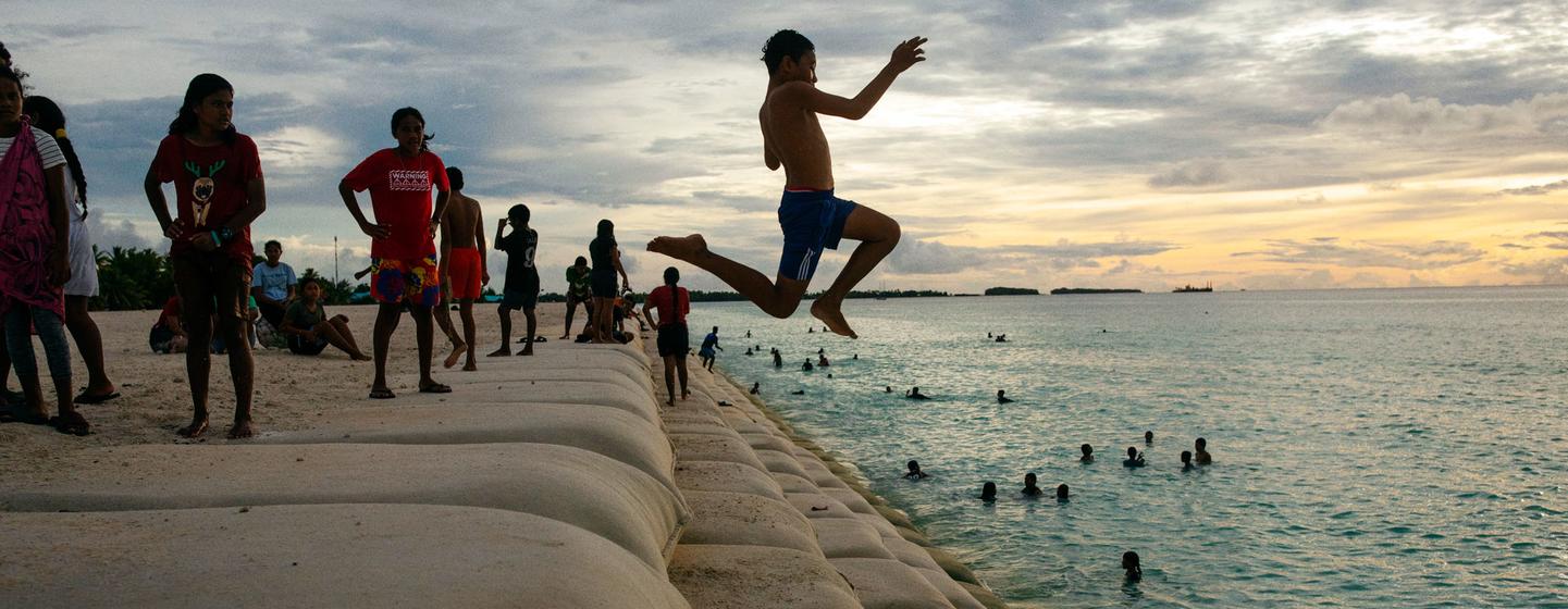 Niños de la isla de Tuvalu, en el Océano Pacífico, juegan en una zona costera protegida por sacos de arena.