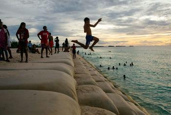 Des enfants de l'île de Tuvalu, dans l'océan Pacifique, jouent dans une zone côtière protégée par des sacs de sable.